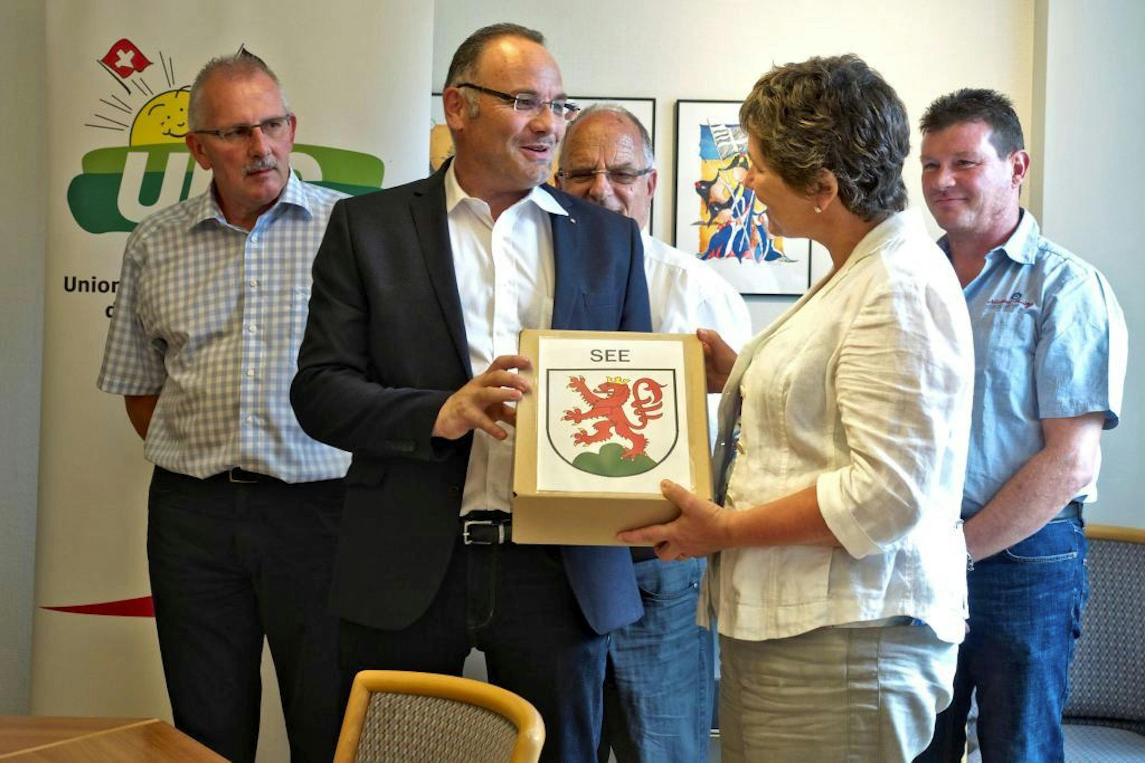 Le président de la section cantonale de l'UDC remet les signatures à la chancelière.