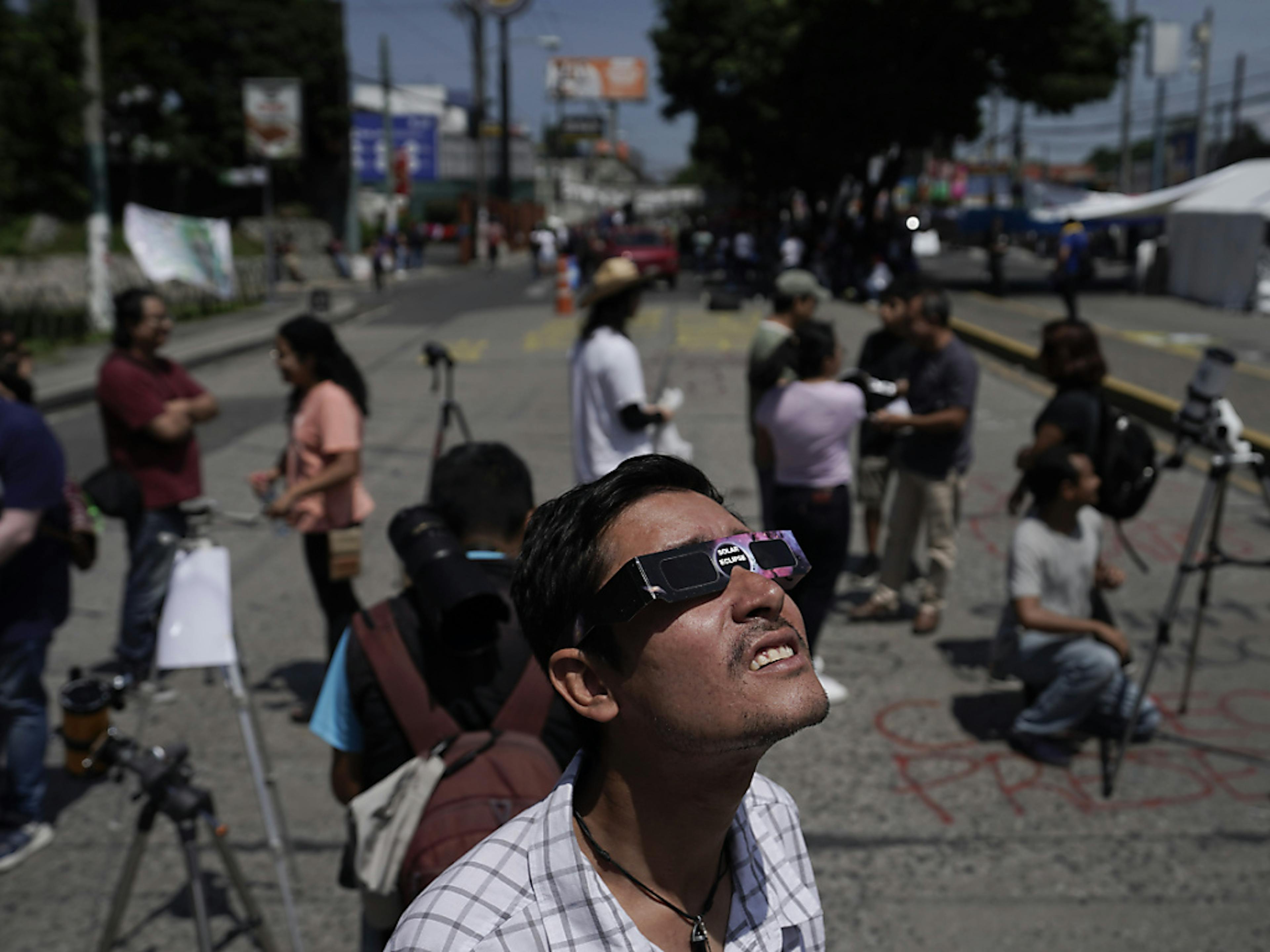 Des personnes regardent l'éclipse à Guatemaly City. La Nasa a martelé qu'il faut porter des lunettes spéciales certifiées pour admirer le phénomène.